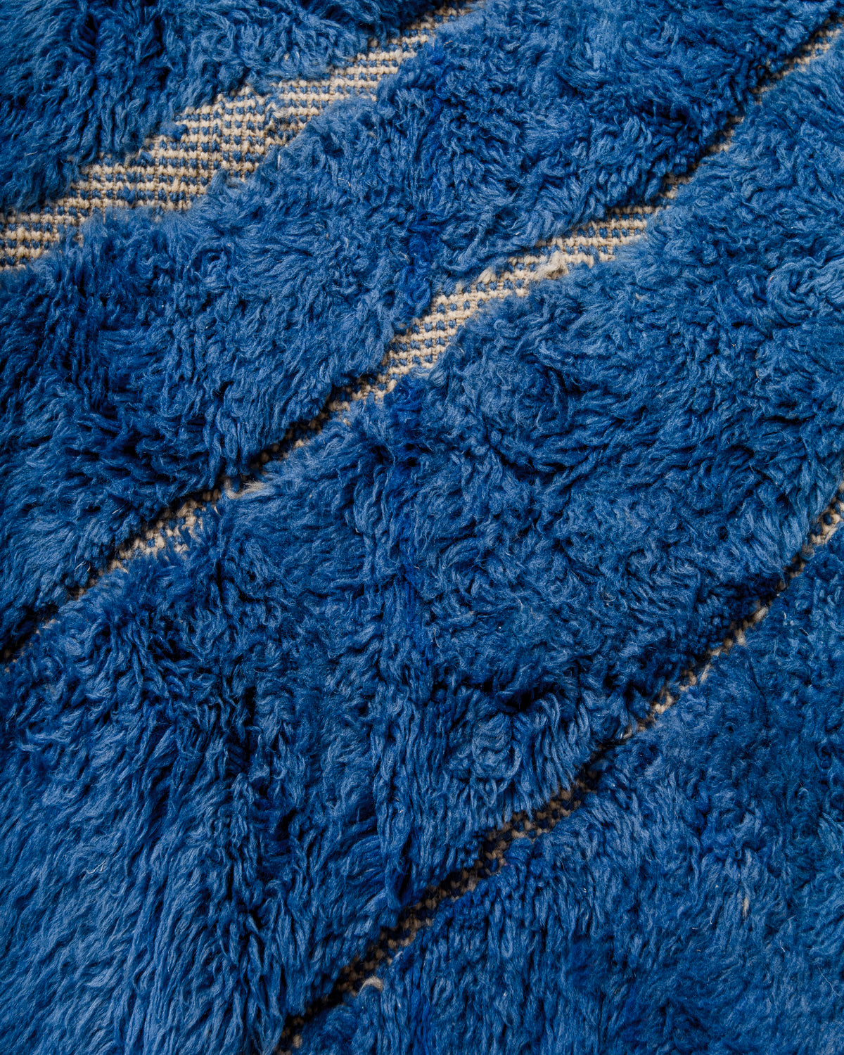 Close up of blue wool beni M'rirt rug with fluffy texture and flat woven lines between.